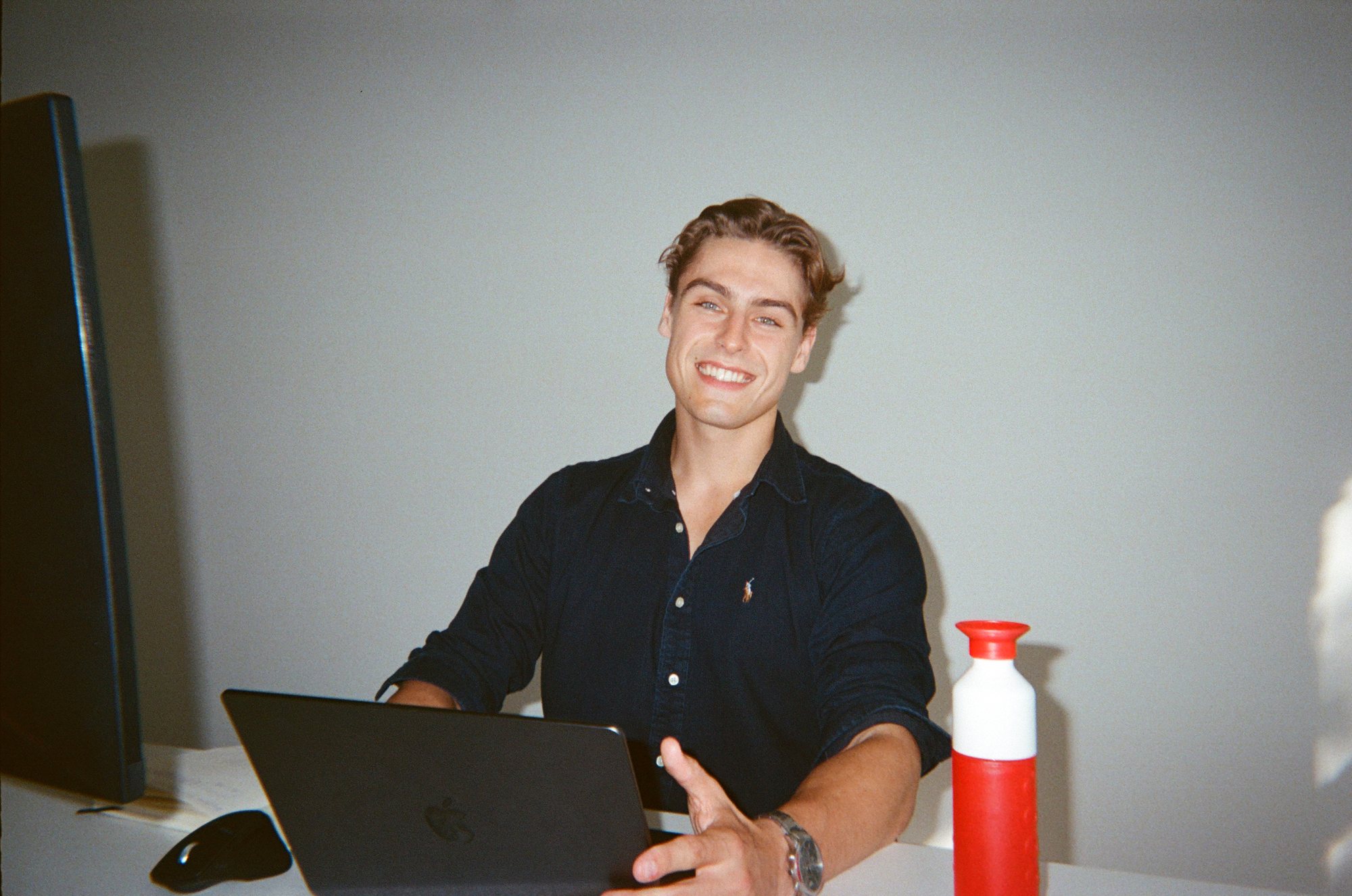 Jonge professional lacht achter zijn laptop